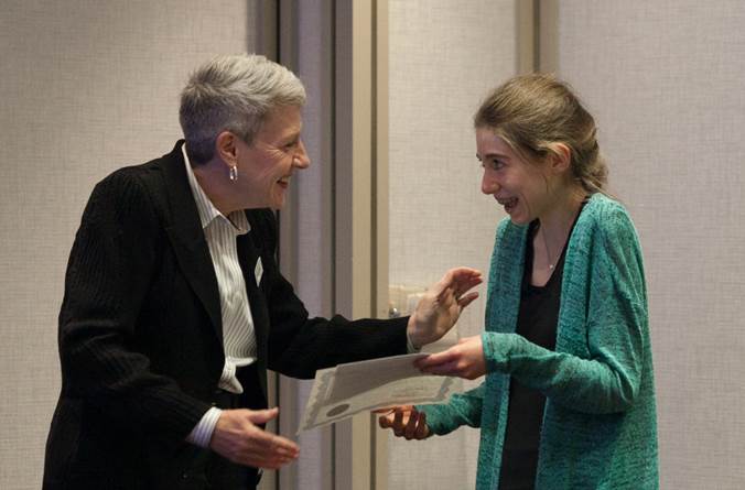 A woman presenting a scholarship to a student