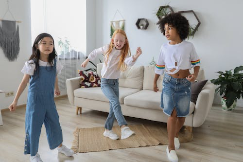 Free Happy multiethnic girlfriends dancing on floor at home Stock Photo