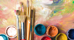 Paint jars and brushes on painted canvas.