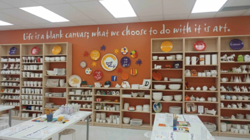 a orange wall with bookshelves. Bookshelves are filled with ceramics