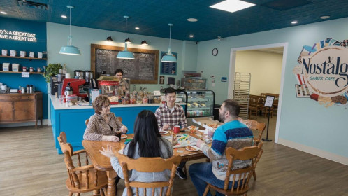 wide angle view of a booards game cafe with a table in the centre and 4 people sitting around it.