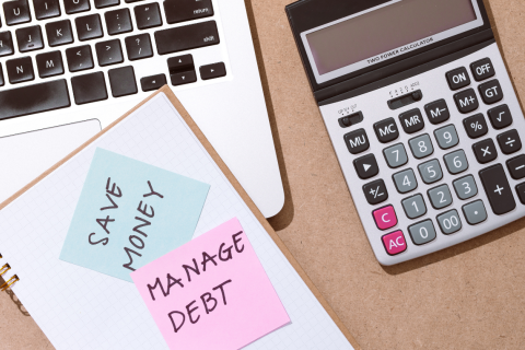 A calculator and notebook tracking money and debt