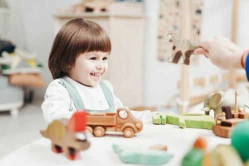 A young child smiling and paying with toys
