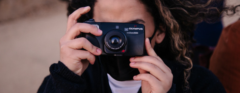 A girl holding a camera up to her face.