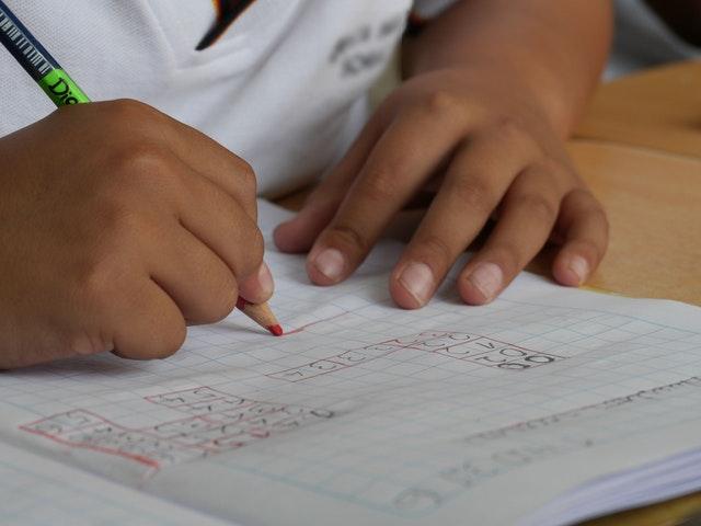 Child's hands writing numbers on a piece of paper