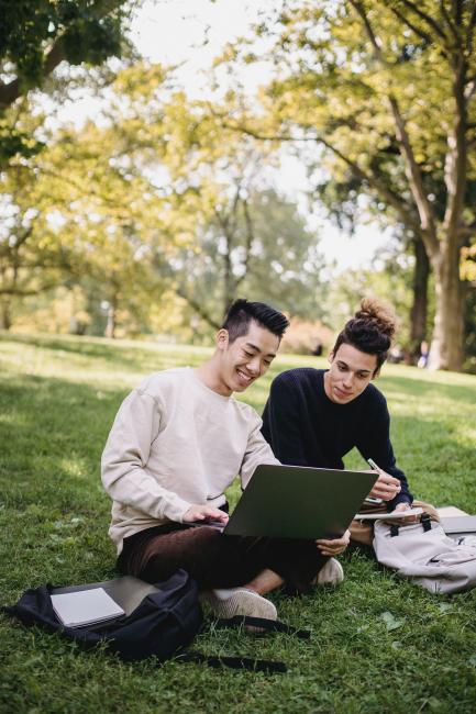 two male students looking at a laptop outside